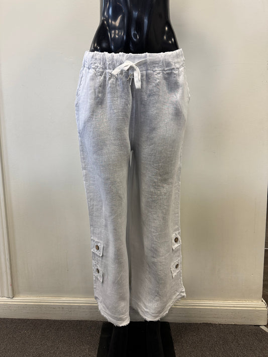 White linen pants (Pants Linen White 4406 - Bella Amore) displayed on a black mannequin against a plain backdrop. These 100% linen pants, crafted in Italy by Bella Amore, feature a drawstring waist and button details at the hems.