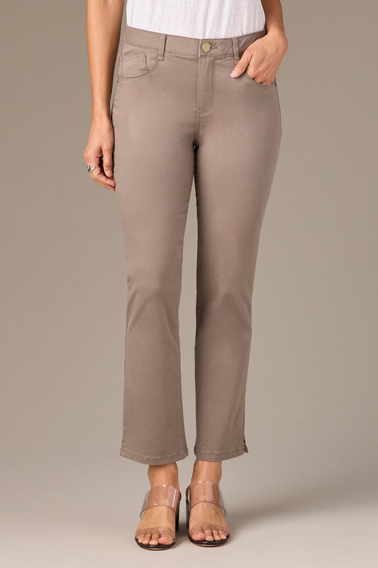 A person in a white shirt wears Wit & Wisdom's Hi-Rise Straight Leg Slit Pant P1009VMX2 BROL from Nordstrom, showcasing a taupe tone and slight ankle flare. They're paired stylishly with clear open-toed sandals against a light brown background.