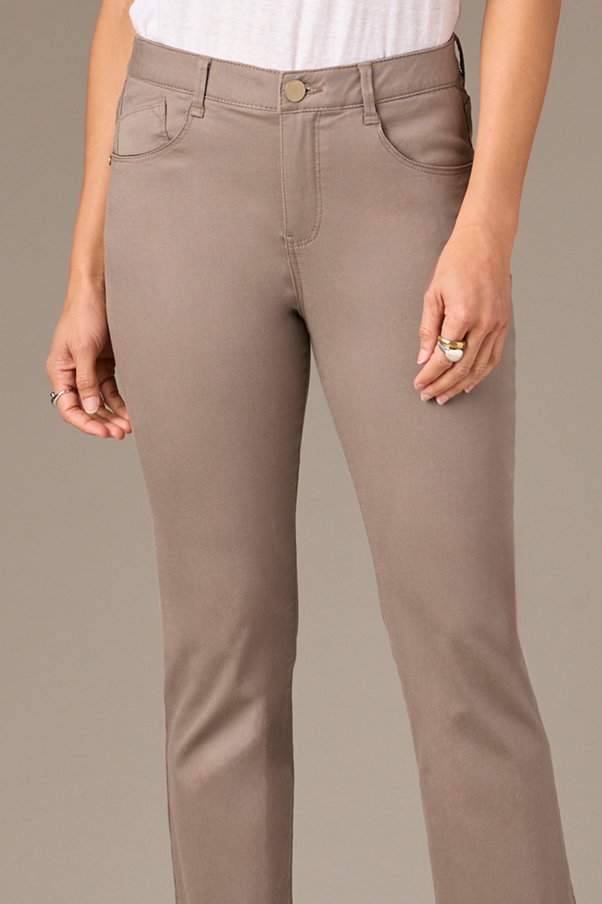 A person in beige Wit & Wisdom Hi-Rise Straight Leg Slit Pants (P1009VMX2 BROL) with a white top wears a gold ring on their left index finger. The simple gray background evokes Nordstrom's minimalist style.