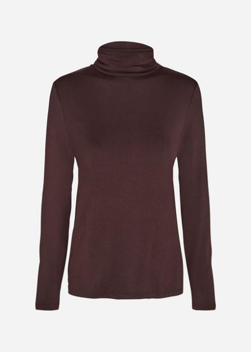 A person stands against a plain white background, arms crossed, wearing a dark brown Soyaconcept SC-MARICA 12 t-shirt, wide-leg black pants, and black ankle boots. Their expression appears neutral, and their body is slightly leaning to one side.