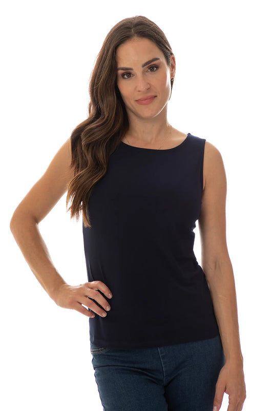 A person with long, wavy brown hair dons Bali Corp's Tank Top 6990, paired with jeans. They pose confidently against a plain white backdrop, one hand on their hip, gazing at the camera.