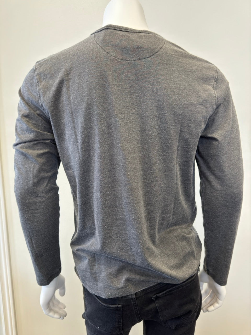 A headless mannequin dressed in the Silver Jeans Co.'s Shirt Long Sleeve - CHARCOAL, featuring a classic 3 button design. This charcoal shirt, made from a 60% cotton and 40% polyester blend, is paired with dark pants to present a casual yet stylish ensemble. The plain white background emphasizes the clothing.
