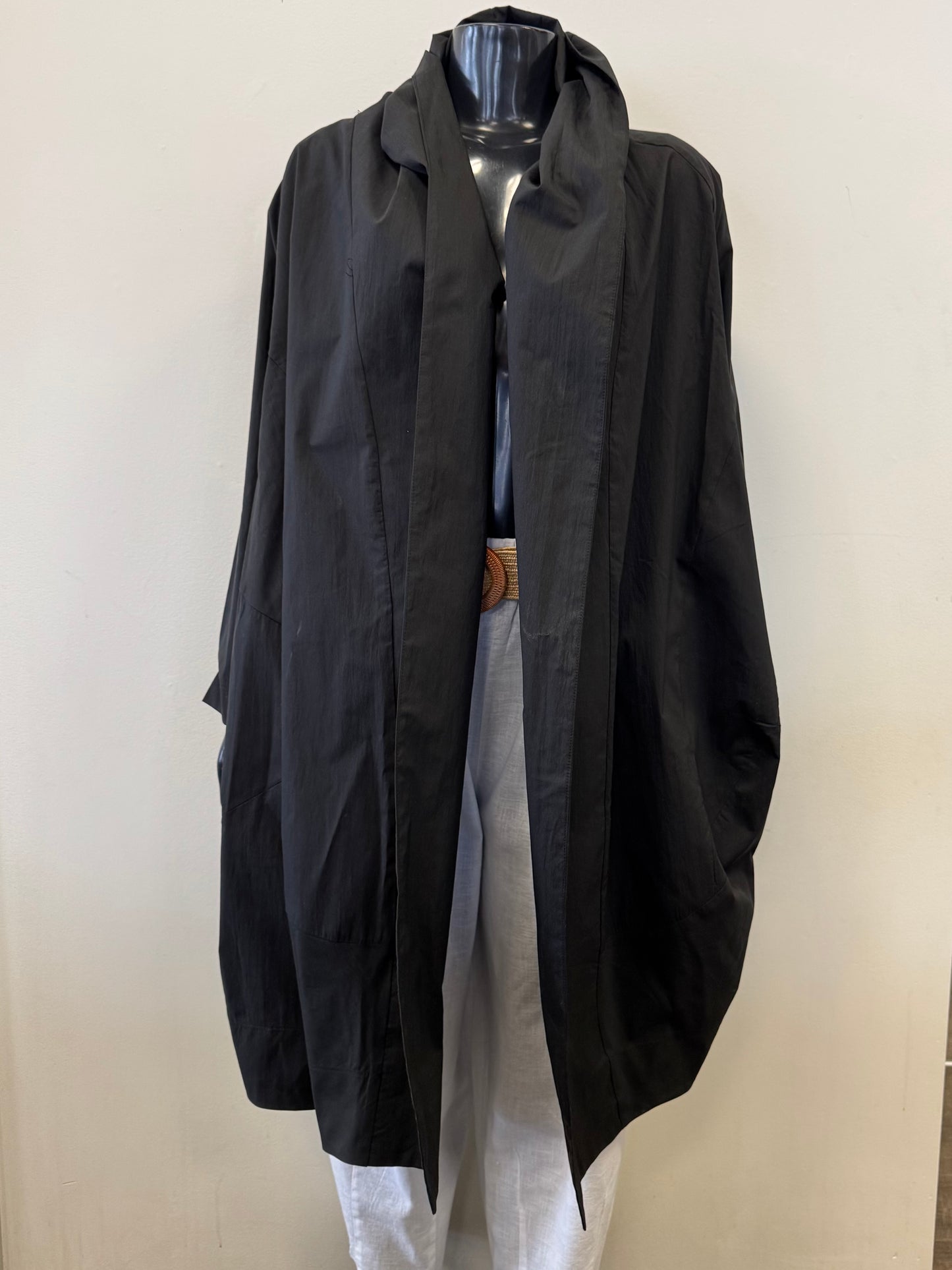 The mannequin showcases the Jacket Coverup WT111016-Pablo Tricot from Paolo Tricot, a loose-fitting long black coat with draped lapels over a black top, paired with light gray trousers against a simple light-colored background.