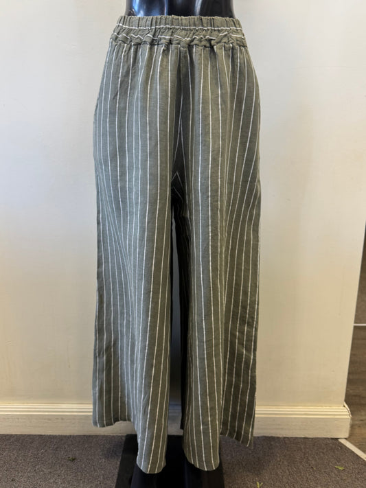 Bella Amore showcases Linen Pants 1045, gray wide-leg pants with green and white stripes, on a mannequin. These pants have an elastic waistband and a loose fit, set against a light-colored wall and carpeted floor.