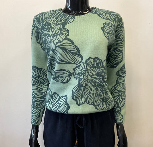 The mannequin displays the SAY IT WITH FLOWERS 15707 sweater by Parkhurst, featuring a cozy design with dark floral patterns. Set against a plain backdrop, this versatile piece boasts long sleeves and a rounded neckline, expertly paired with dark pants.