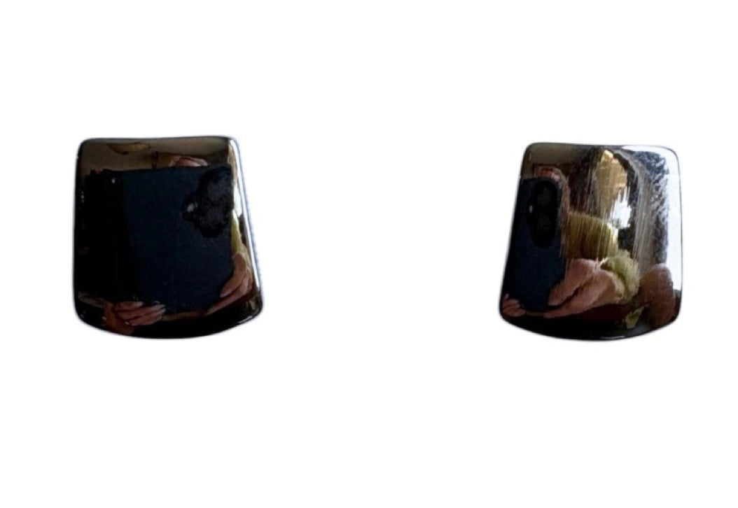 Two shiny, black, slightly curved rectangles set against a white background reflect a person wearing Doris 14 Silver Clip-on Earrings by Elise Accessories. The small square shape hints at stylish costume jewellery from Elise accessories.