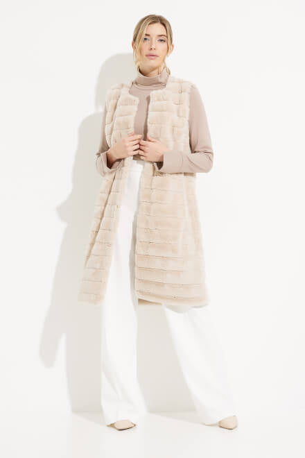 Close-up of a person's hand tucked into the pocket of a Joseph Ribkoff Faux Fur Longline Vest, Style 233924. The luxurious beige vest features horizontal ribbed patterns. The person is wearing a long-sleeve beige top that partially covers the wrist. The image has a clean, white background.