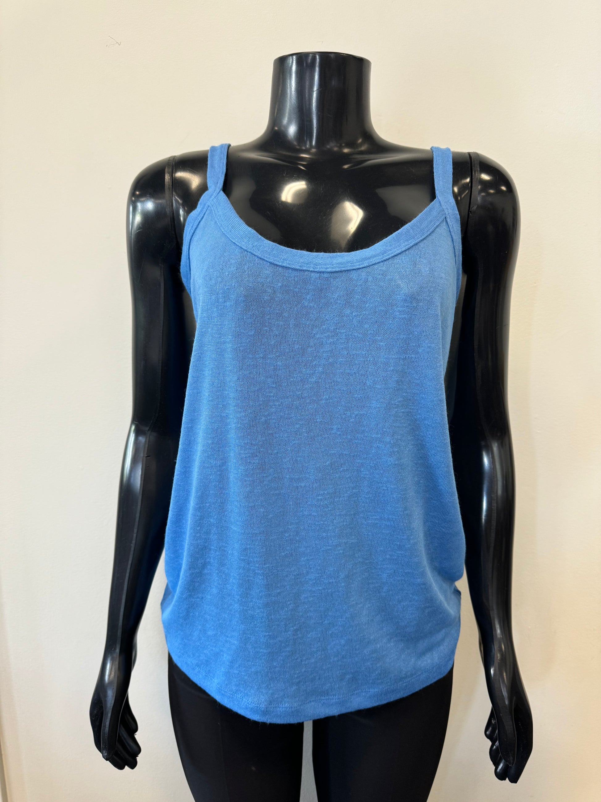 A black mannequin is showcasing a sleeveless, loose-fitting, blue tank top with a scooped neckline. The backdrop features a plain off-white wall. This stylish piece, part of the MARBLE Tank with Cover Top and Scarf set (Product Code: 6551 Marble), boasts thin shoulder straps and a simple, casual design.