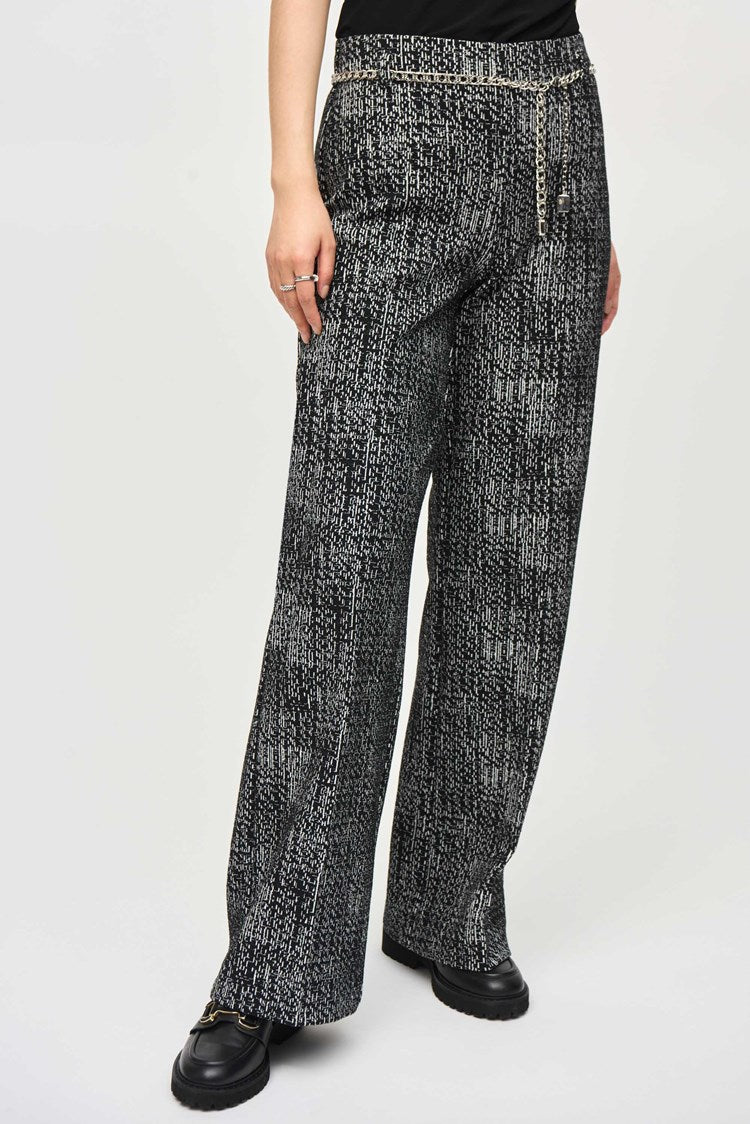 A person with long, straight black hair and bangs stands against a plain background. They are wearing a black and white patterned tweed knit fabric blazer with matching wide-leg pants, specifically Tweed Knit Wide-Leg Pull-On Pants 243288 by Joseph Ribkoff, and black shoes. They have an expressionless face, and their hands are relaxed by their sides.