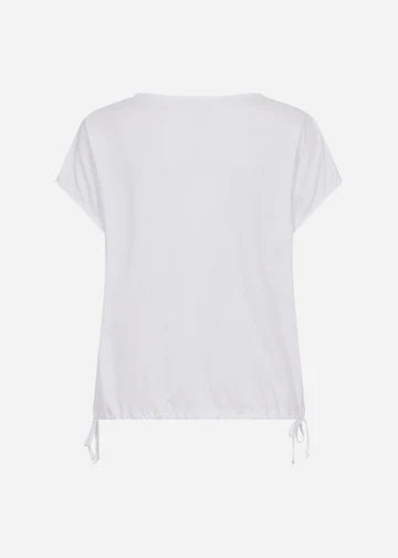 A person with long, blonde hair is wearing a white SC-DERBY 33 T-SHIRT from SoyaConcept, featuring a round neckline. They have paired it with yellow drawstring pants and are standing against a plain, light-colored background. Their expression is neutral as they look directly at the camera.
