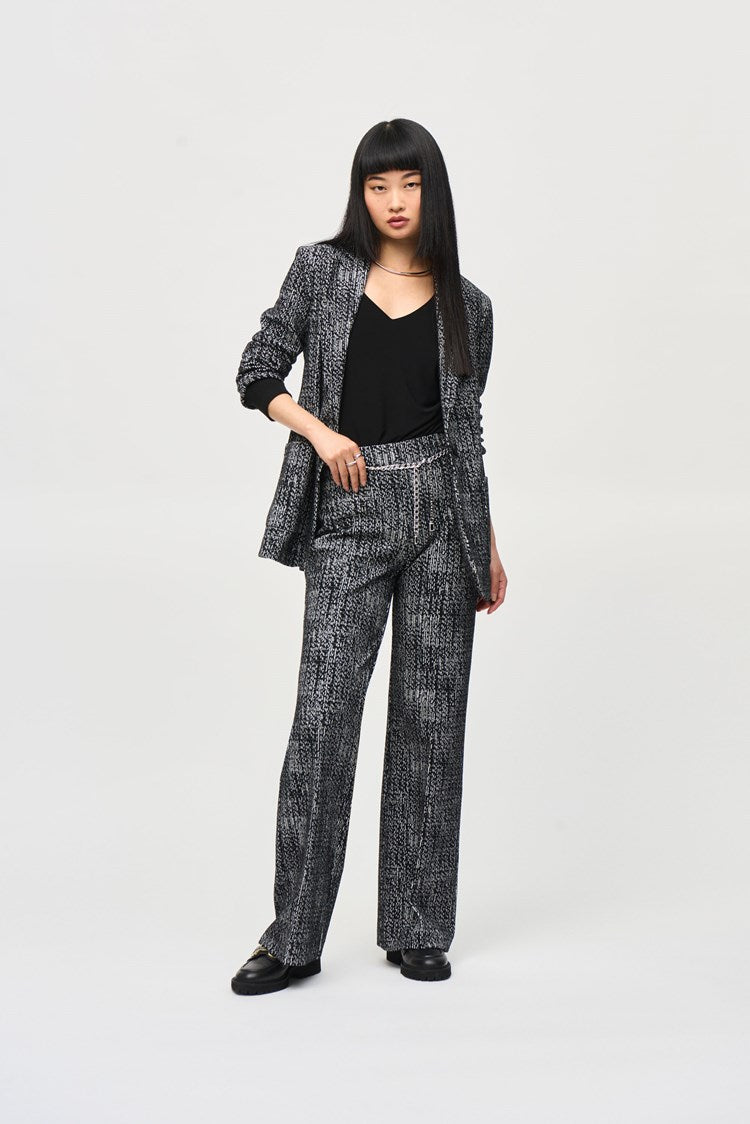 A person with long, straight hair stands against a plain backdrop wearing a matching dark patterned Joseph Ribkoff Tweed Knit Fitted Blazer (243053) and wide-leg pants with a textured design, embodying the elegance of a versatile fashion piece. Their hands are relaxed at their sides as they look slightly to the left with a neutral expression.