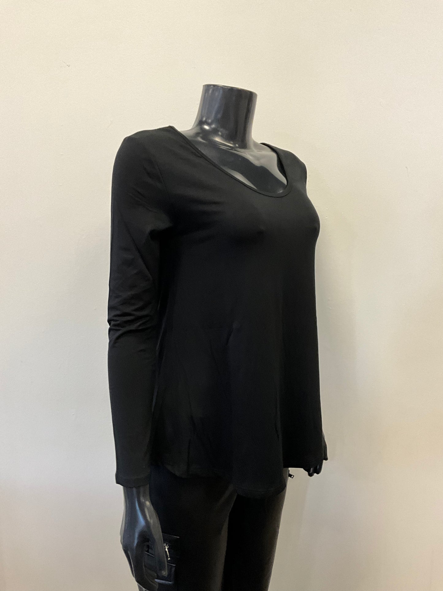 A black mannequin dressed in an ETERNELLE Top Round Neck - Eternelle, a long-sleeved white shirt with a scooped neckline and a slightly flared bottom. The elegant garment, meticulously crafted in Italy, is set against a plain, light-colored background. Only the upper torso of the mannequin is visible, with no accessories in sight.