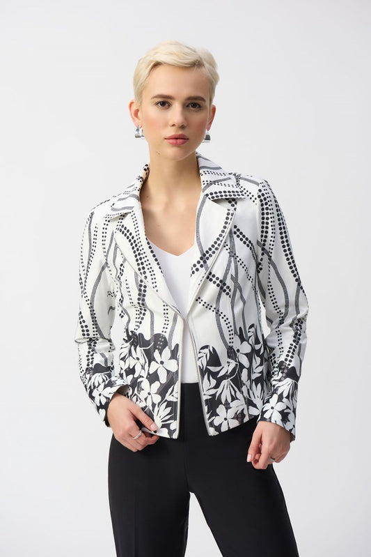 A person with short blonde hair wears the Joseph Ribkoff Faux Suede Floral Print Jacket 251910, featuring black abstract and floral prints with a notched collar, over a white top and black pants against a light gray backdrop.