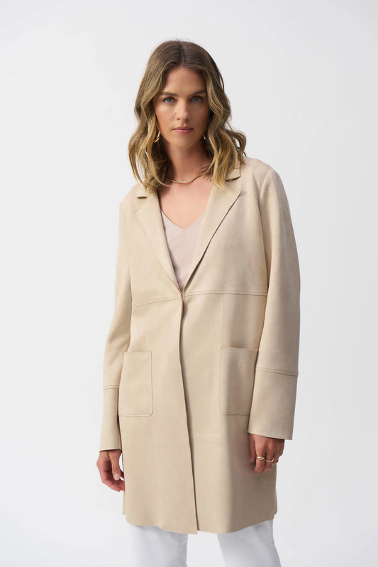 A woman with wavy, shoulder-length hair wears the Joseph Ribkoff Scuba Suede Straight Jacket 251941, featuring patch pockets and a notched collar over a light top. She stands against a plain white background, looking directly at the camera with a neutral expression.