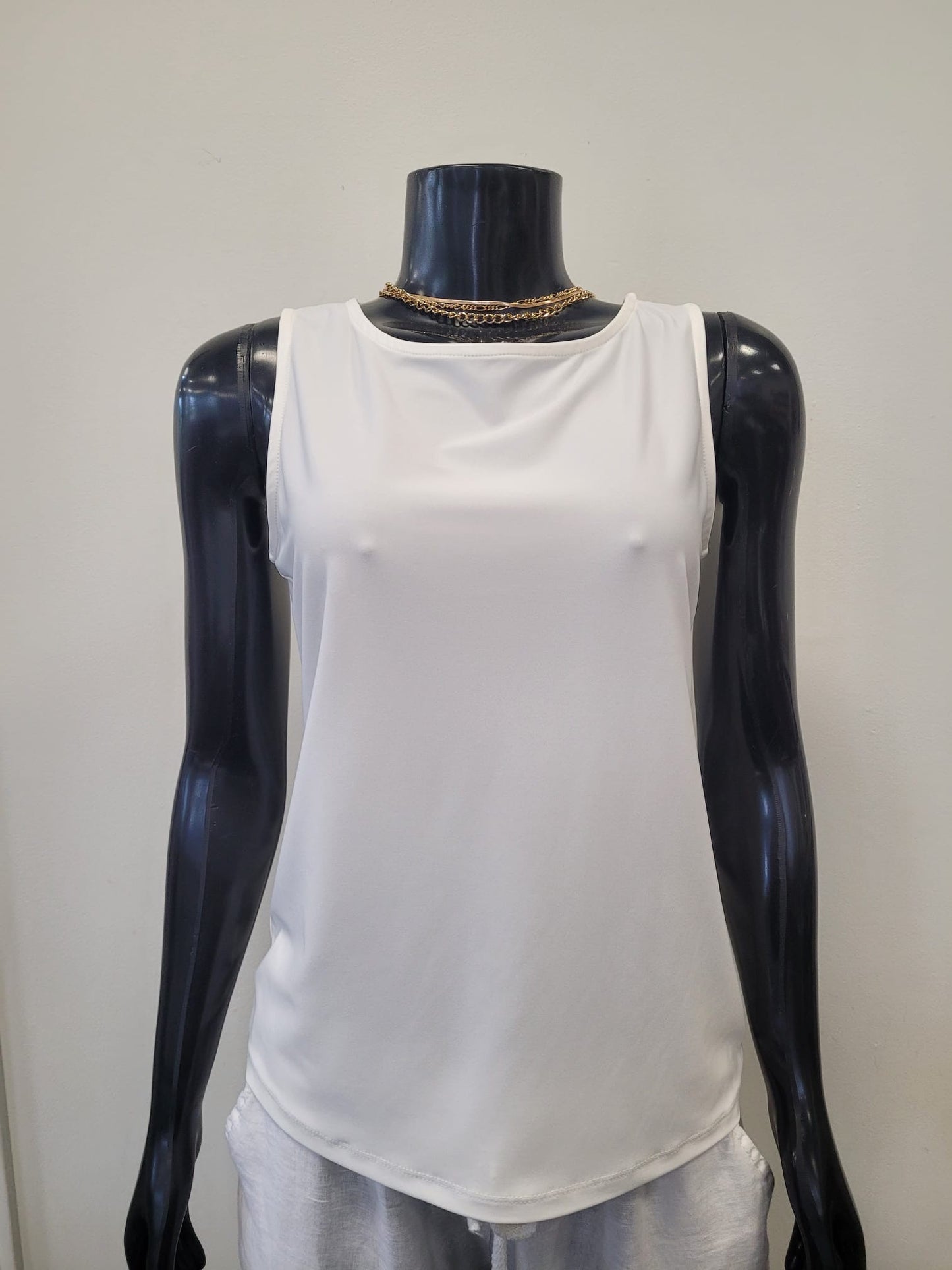 A black mannequin wears the Tank Top 6990-Bali Corp, a creamy white round neck design by Bali Corp, styled with a gold chain necklace against a plain light background.