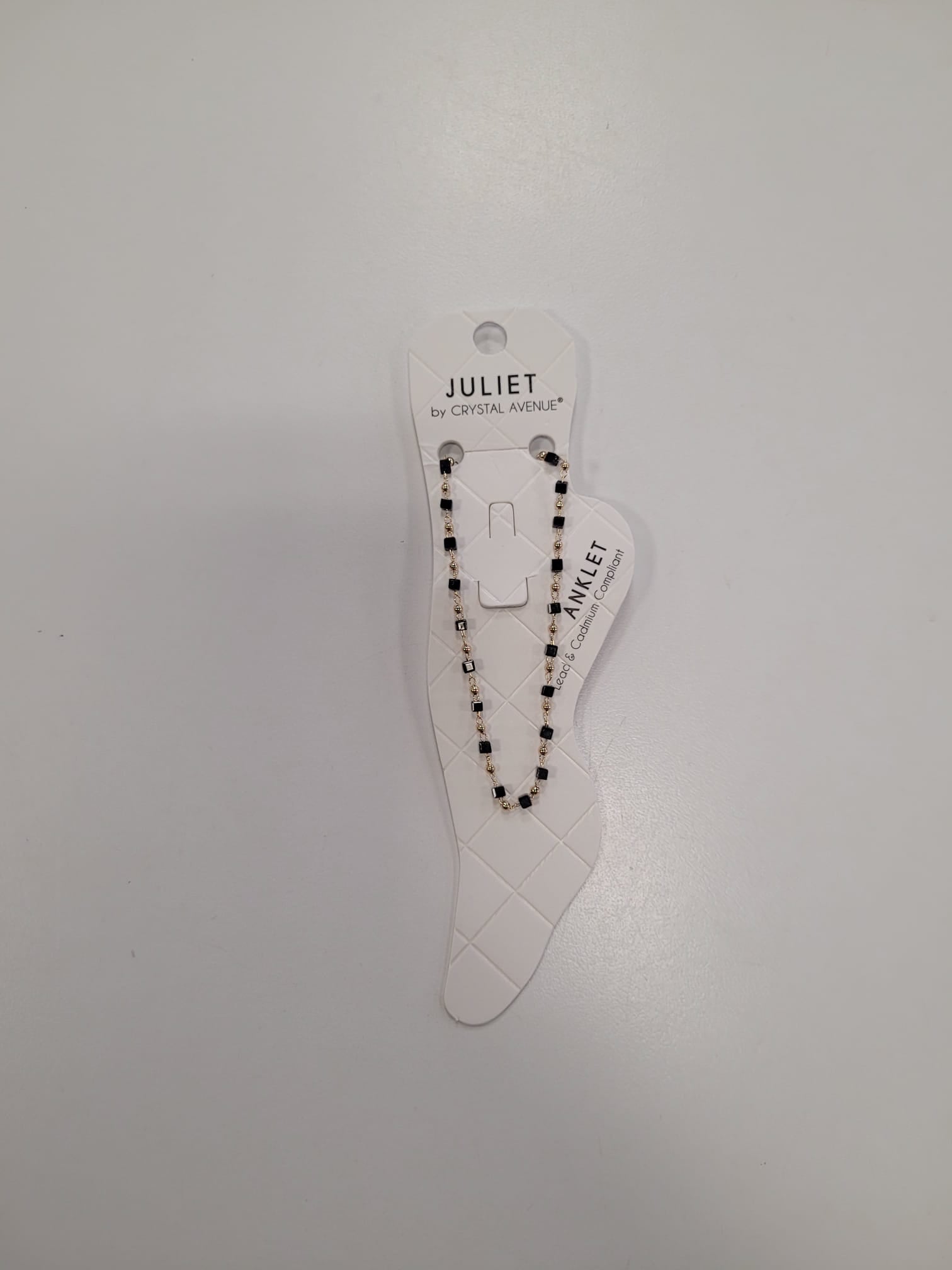 A beaded anklet with black and white beads on a foot-shaped display card, labeled “JULIET BY CRYSTAL AVENUE,” makes a perfect match for your favorite Angela 4 Anklet by Elise accessories.