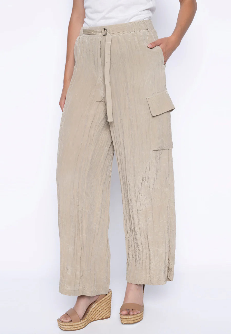 A person wears Joseph Ribkoff's Wide-Leg Cargo Pants GM027 - PICADILLY, textured woven, high-waisted, beige with large side pockets. With one hand in a pocket and the other bent, they stand in wedge sandals against a white background.