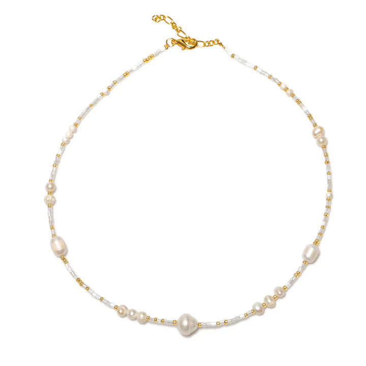 The Suzie Blue Large Pearl & Bead Short Necklace showcases a delicate arrangement of irregularly shaped white pearls interspersed with small gold beads and cylindrical white beads. Handmade with care, this necklace is fastened with a gold clasp, ensuring each component is ethically sourced.