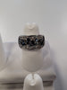 The Jenna-62 Adjustable Ring by Elise Accessories is a stylish piece adorned with multiple black gemstones arranged in a floral pattern. It is beautifully displayed on a white ring stand against a white background.