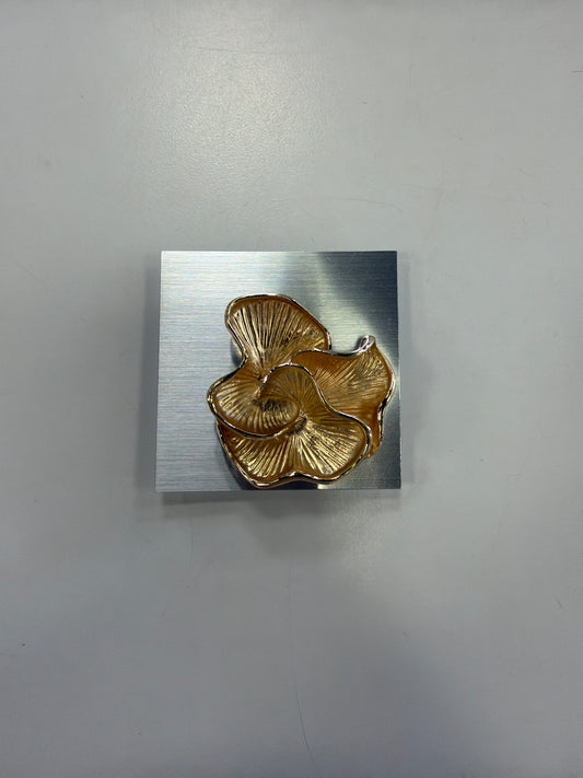 Denise 24 Brooch featuring a gold-toned, flower-shaped pin mounted on a square, brushed silver metal plate with a magnetic back.