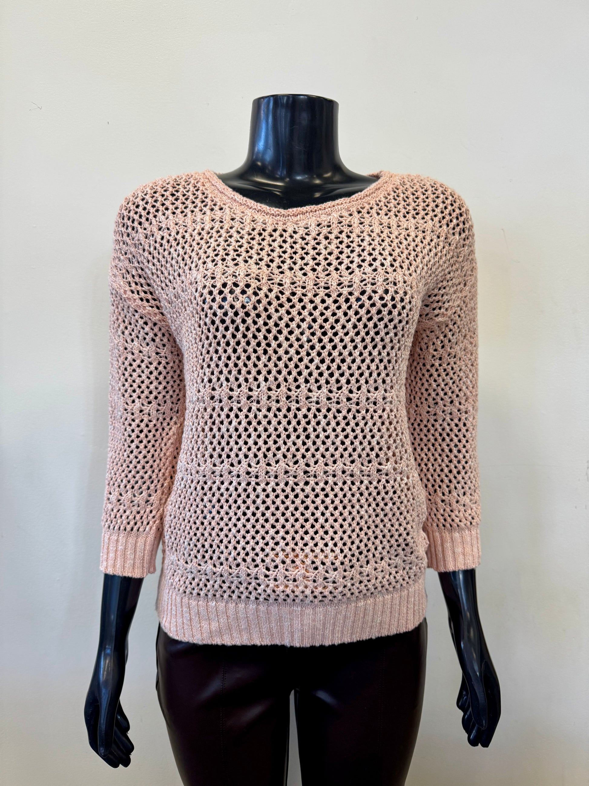 A black mannequin displays the Parkhurst Eco Mesh Top 75336, a pink, open-knit sweater with long sleeves and a round neckline. Ideal for eco-conscious fashionistas, it's paired with dark pants against a plain background, epitomizing sustainable style.