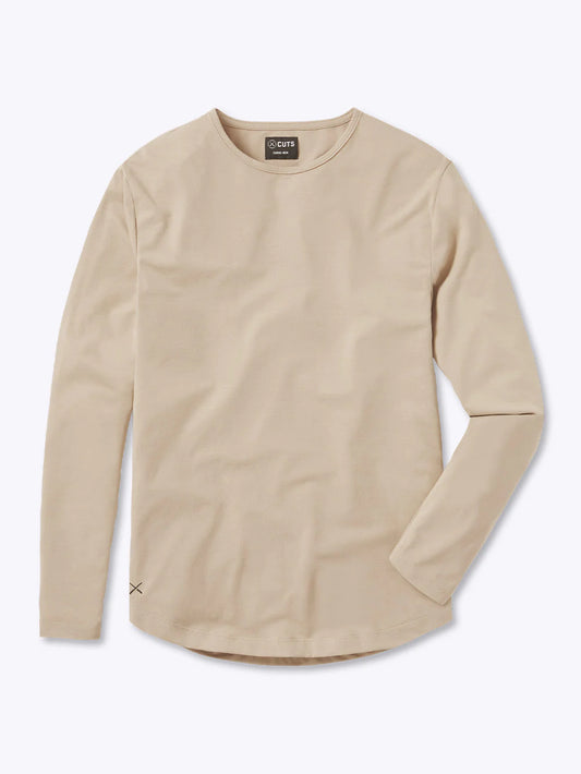 A beige AO Long Sleeve Curve-Hem tee is laid flat on a white background. This signature-fit t-shirt by CUTS features a simple design with a rounded neckline and is crafted from PYCA Pro fabric. A small tag near the collar displays the brand name, "CUTS".