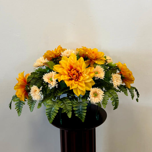 The 5 - Tombstone Saddle 60 cm Length by Posies Flowers & Fashion Inc. features large yellow and orange flowers, cream blooms, and green ferns in a dark vase—ideal as a memorial saddle arrangement for honoring loved ones.