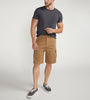 A man stands against a plain background wearing a dark gray t-shirt with a chest pocket, relaxed fit CARGO SHORT DESERT styled by Silver Jeans Co. (product code: M53151CBT639), and black sneakers with white soles. He appears to be adjusting his shirt with his right hand.