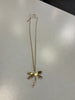 The Ava 22 Gold Necklace from Elise Accessories, featuring a hammered dragonfly-shaped pendant, is displayed on a white surface with a price tag attached to the chain near the top.