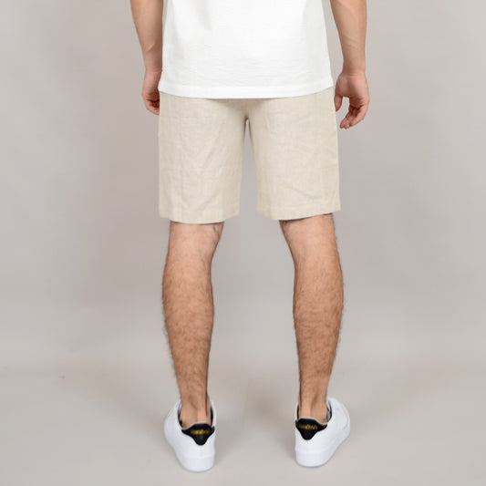 A person stands with their back to the camera against a plain light background, wearing a white shirt, white sneakers with black detail, and HEDGE Linen Blend Shorts Natural 41MW507S.