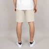 A person stands with their back to the camera against a plain light background, wearing a white shirt, white sneakers with black detail, and HEDGE Linen Blend Shorts Natural 41MW507S.