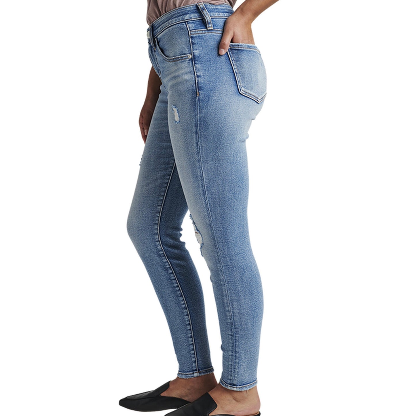 A person is wearing the Cecilia Mid Rise Skinny Jeans by JAG, which are light blue, high-waisted skinny jeans made with power stretch denim and featuring distressed details around the knees and thighs. These jeans have a button and zip closure, belt loops, and pockets. The person is also wearing black, closed-toe shoes and a tucked-in shirt.