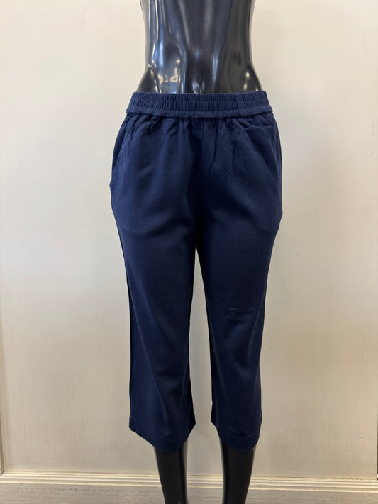 The Pant 6081 by SUNDAY is displayed on a black mannequin, showcasing navy blue cropped pants made from a linen-viscose blend with an elastic waistband, set against a plain pale wall.
