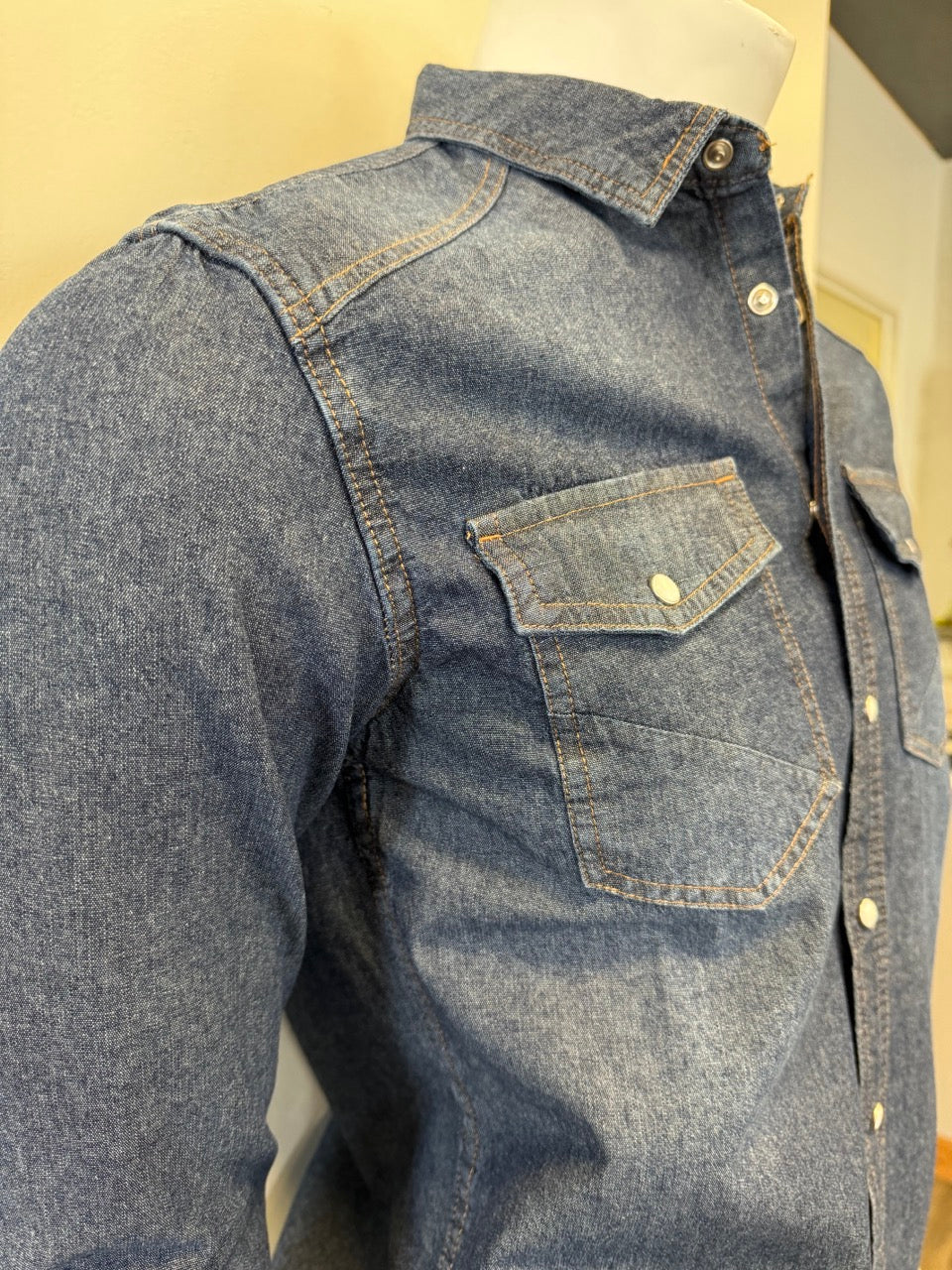 Mannequin dressed in a Silver Jeans Co. Denim Shirt Long Sleeve - MEDIUM WASH, featuring white buttons and two buttoned chest pockets. The 100% cotton shirt is displayed against a plain background, with the mannequin's lower half partially visible, wearing dark pants.