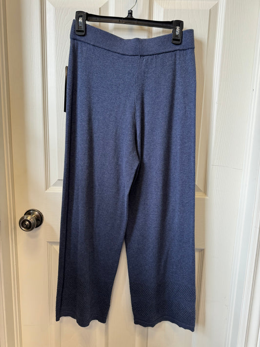 A pair of versatile Tribal Dark Navy Casual Pants - 4828O-576-0657 hangs on a black plastic hanger attached to a white door. The full-length pants, made by the brand Tribal from 100% cotton, feature a straight cut design with subtle patterns near the hem. The door has a silver doorknob on the left side.