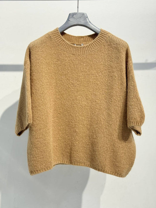 A camel-colored, oversized knit sweater—NOELINE’s 6004 kid mohair and wool sweater—is displayed on a hanger against a plain white wall.