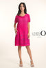 A woman in the LinenO French Linen Dress TP1745-43 Fuxia, featuring short sleeves and floral embroidery, poses confidently in white heels against a light background. "LINEN ORIGINS" appears beside her.