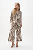 A person stands against a plain background in the Joseph Ribkoff Linen Blend Animal Print A-Line Blouse 262943 and matching wide-leg pants, featuring a bold brown and white animal print for a striking, fashion-forward look.