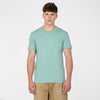 A young man with short brown hair wears the RAGWEAR T-shirt NEDDIS C 2612-15023-5036 in Dusty Green, paired with tan shorts, standing against a white background and embodying vegan streetwear style.