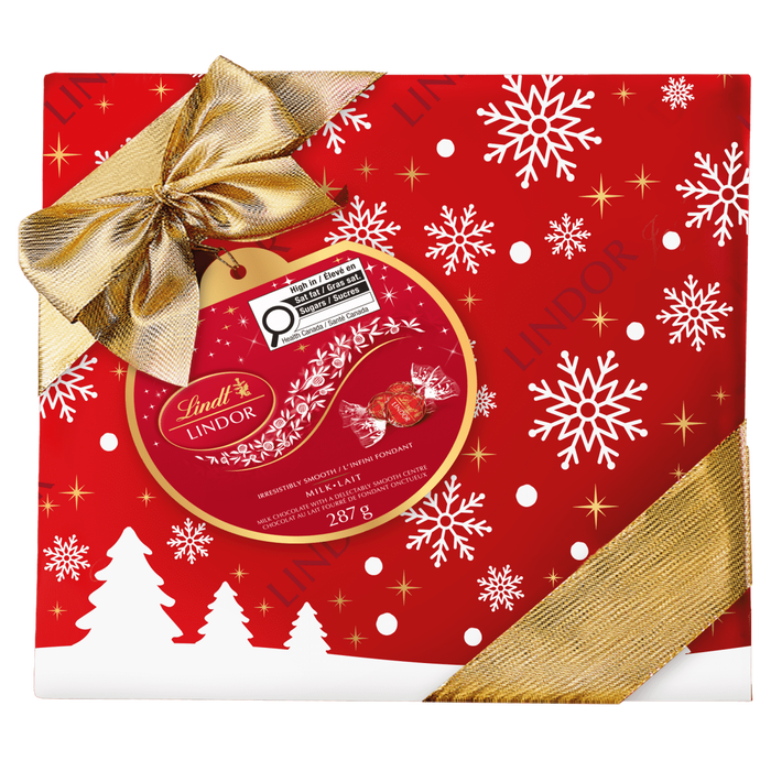 The Lindt Lindor LINDOR Milk Chocolate Truffles Gift Box, 287g, features festive red packaging with white snowflakes, gold stars, tree silhouettes, and a gold ribbon—perfect for holiday gifting with signature milk chocolate truffles.