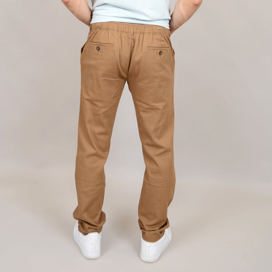A person stands with their back to the camera against a plain, light background, wearing HEDGE’s Twill Pant 41MW602S in a soft cotton-spandex blend and white sneakers.