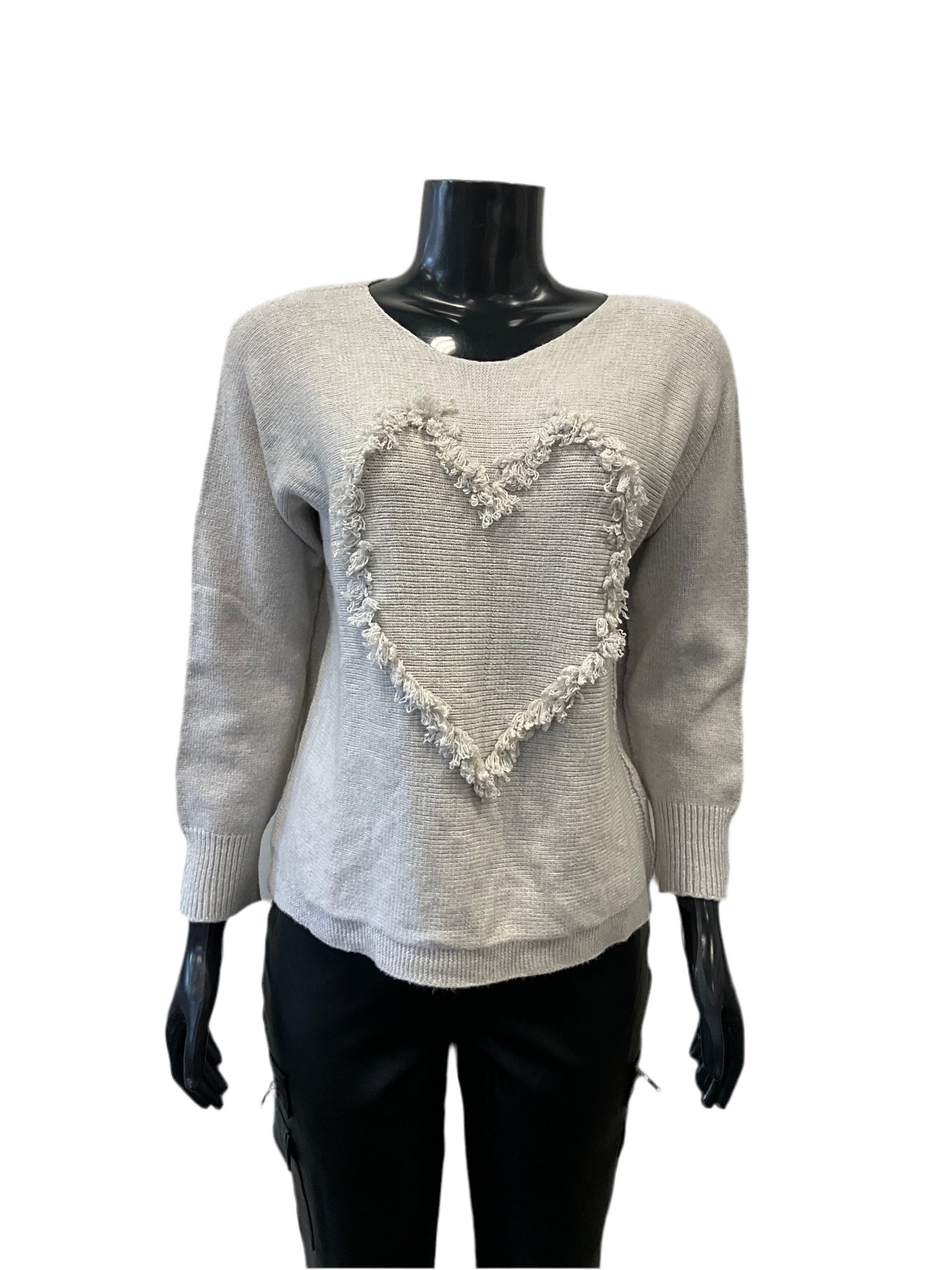 A Round Neck Sweater with Heart Design Grey/Beige by ETERNELLE is displayed on a black mannequin. The sweater, made in Italy, features a large heart design made of frayed fabric on the front, giving it a textured appearance. The mannequin is also wearing black pants.