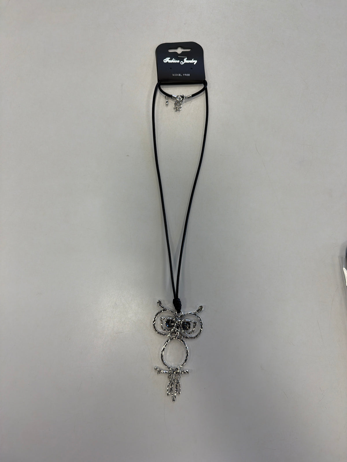 A whimsical silver owl-shaped Sofia 49 Necklace on a long black cord.