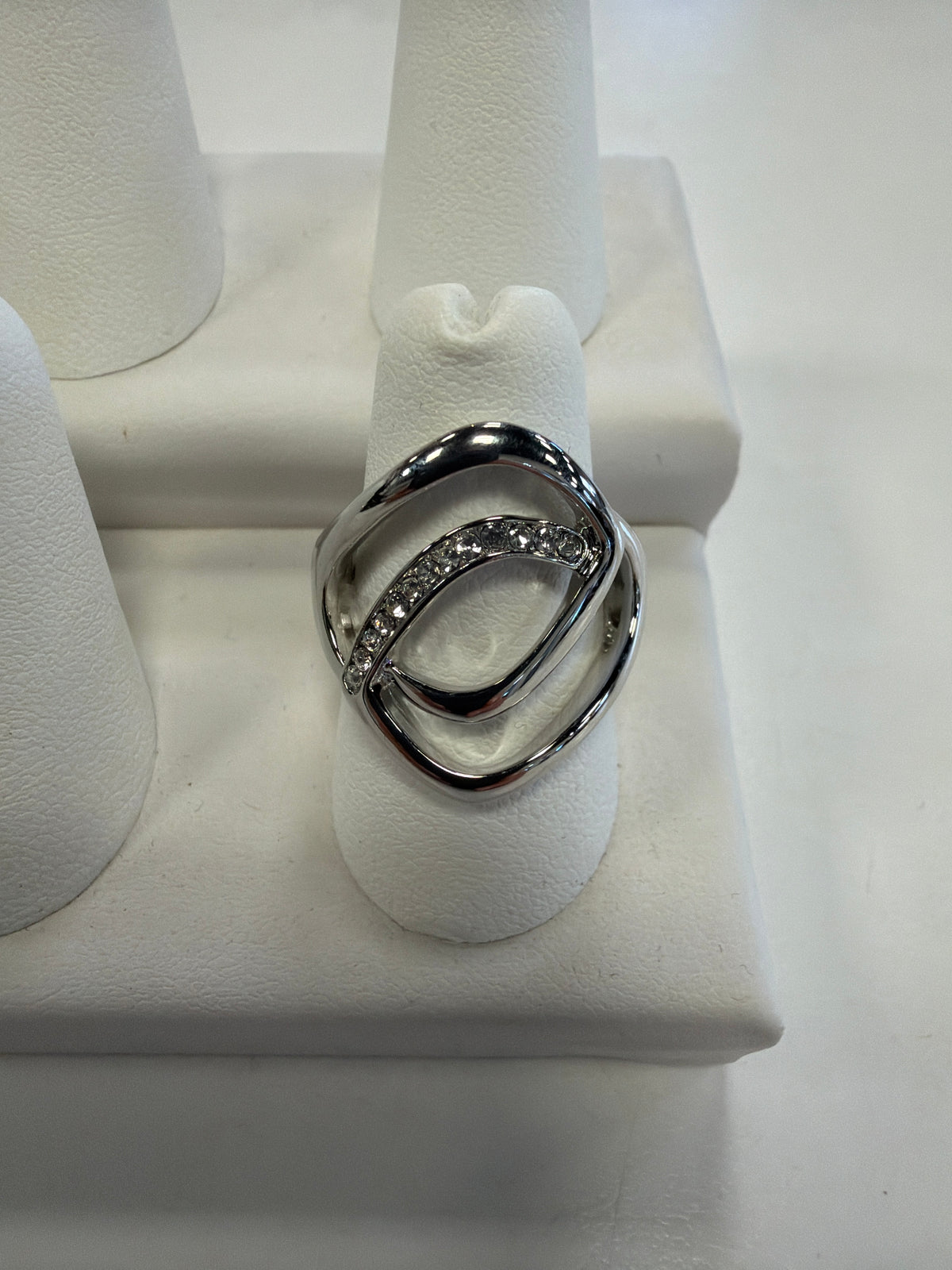 Jenna 58 Ring in silver, featuring an abstract, overlapping oval design with a row of clear stones set into one side of the stretch band.