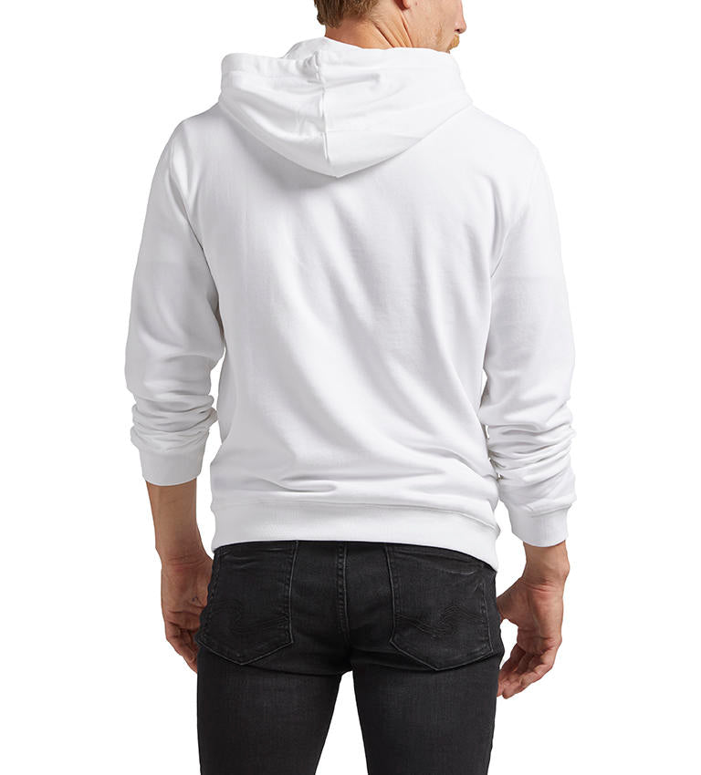 A person is wearing the Silver Jeans Co. Logo Hoodie - WHITE, a white French terry hoodie with drawstrings, a front pocket, and an embroidered logo featuring text and coordinates on the front. The 100% cotton hoodie pairs perfectly with their black jeans and beard. Only the upper body and part of the legs are visible.