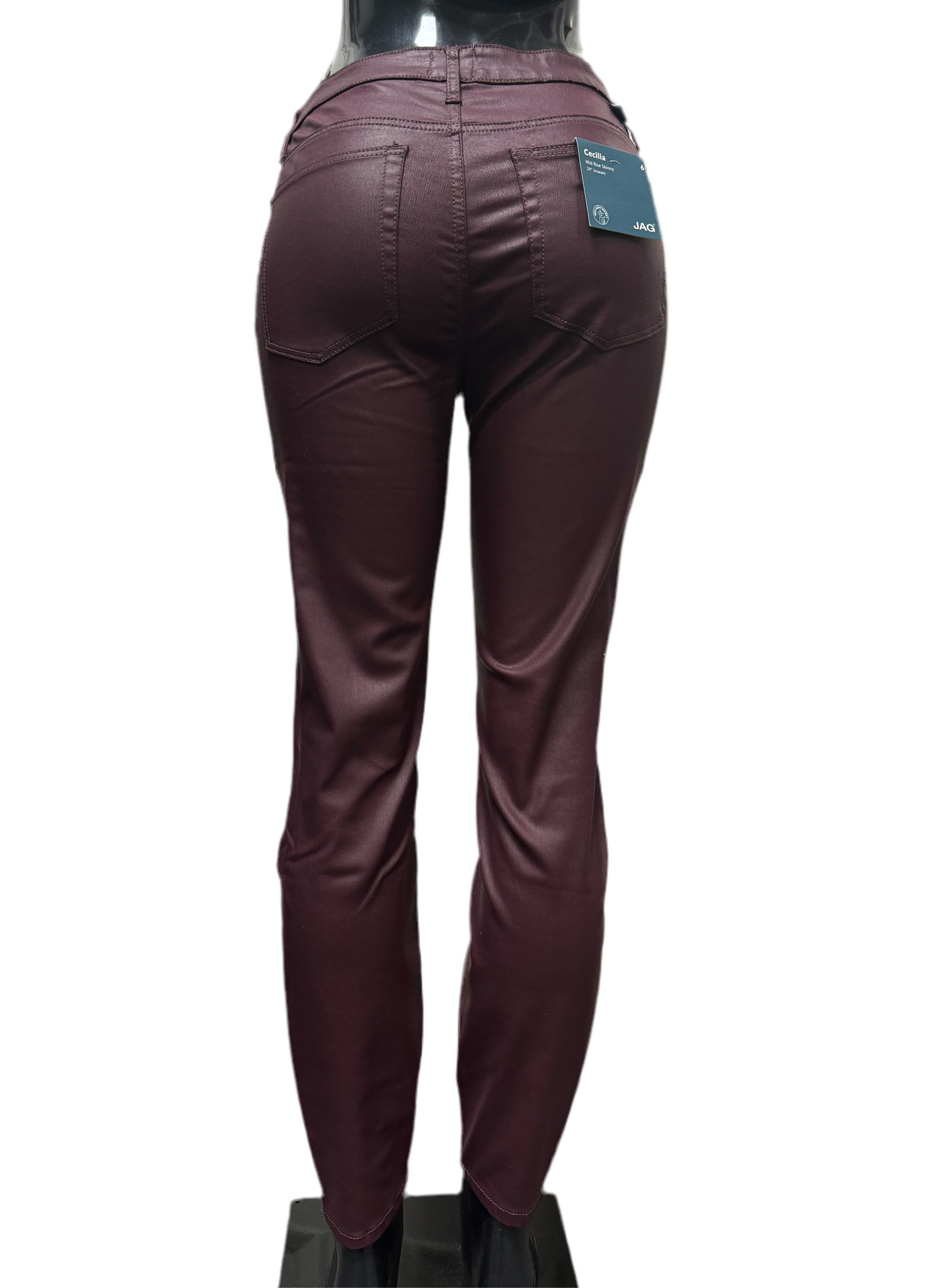 A mannequin is wearing a pair of JAG Cicilia Skinny Bordeaux pants. The burgundy, mid-rise pants have a shiny finish and feature two back pockets with stitching details and an attached tag near the waistband. An interior elastic waistband offers extra comfort. The mannequin is displayed against a white background.