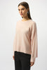A woman with straight brown hair wears the Joseph Ribkoff Cashmere Crew Neck Top with Stud Detailing 253980 and dark pants, standing against a plain light background and looking slightly to the side.