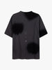 The Maddox Tee - CAMO DESERT DARK SHADE from Once We Were Warriors is a short-sleeve t-shirt featuring a loose fit and a crew neckline. Crafted from premium cotton, it showcases abstract dark patches and subtle vertical text motifs in the center of the back, enhanced by an artistic spray design. The texture appears soft and smooth.