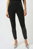A woman wears Joseph Ribkoff's Heavy Knit and Leatherette Pull-On Legging 253078 with leather-like thigh and calf panels, paired with a bracelet and metallic silver pointed-toe heels, standing against a plain white background.
