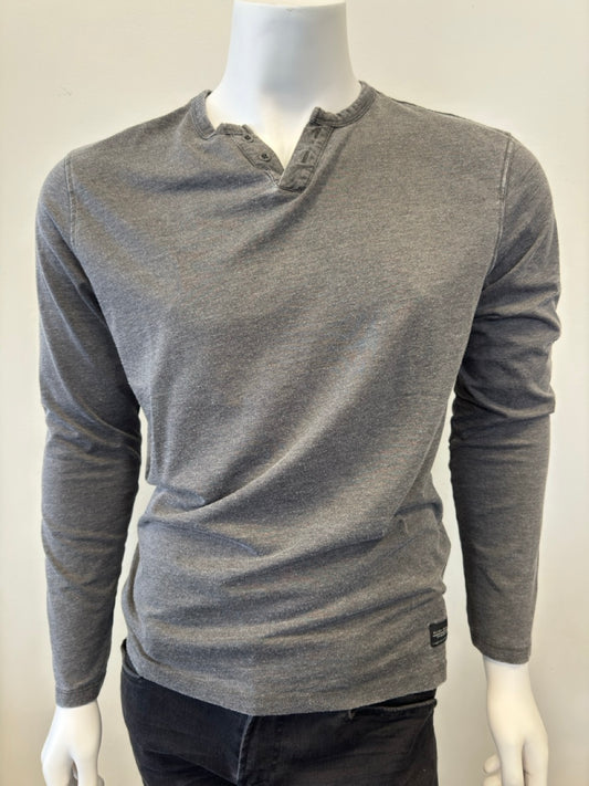 A headless mannequin dressed in the Silver Jeans Co.'s Shirt Long Sleeve - CHARCOAL, featuring a classic 3 button design. This charcoal shirt, made from a 60% cotton and 40% polyester blend, is paired with dark pants to present a casual yet stylish ensemble. The plain white background emphasizes the clothing.